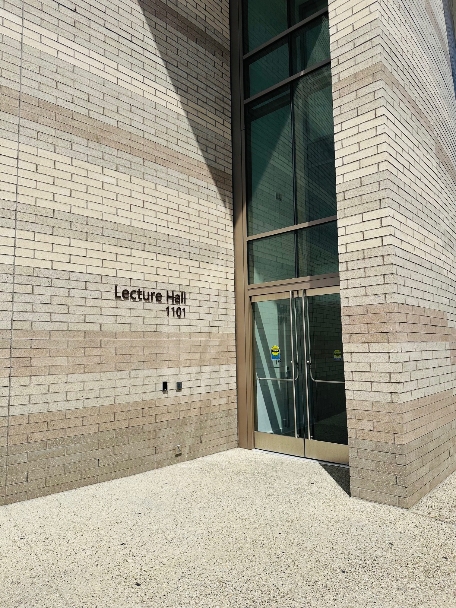 a beige brick building with glass doors and the room number (1101) to the left